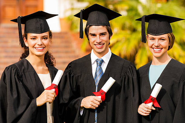 Portrait of happy multi-ethnic students holding certificates on graduation day in college. Horizontal shot.